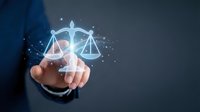 Businessman in dark suit touching glowing scales of justice hologram with particles, representing legal compliance, law, ethics, and fair business practices.