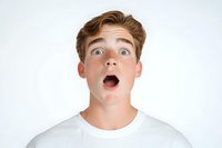 Young Caucasian male with shocked facial expression wearing white t-shirt against light background, displaying surprise and astonishment with wide open mouth and eyes.