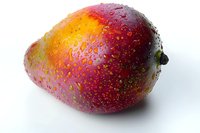 Fresh ripe mango with water droplets on red purple skin isolated on white background, perfect for food marketing, packaging design and healthy eating concepts.