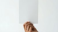 Hands holding blank white paper card against neutral background for mockup presentations and branding materials.