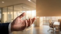 Businessman hand gesture welcoming or presenting in modern office space with glass partitions and warm sunlight, suitable for corporate communication and business concepts.