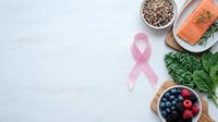 Healthy nutrition concept with pink ribbon, fresh salmon, quinoa, kale and berries for cancer awareness and prevention diet on white background.
