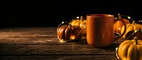 Copper mug surrounded by decorative gourds on rustic wooden surface against dark background, suitable for fall beverage and seasonal marketing campaigns.