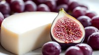 Fresh figs and grapes surrounding creamy white cheese on dark background, macro food photography highlighting texture and natural ingredients.
