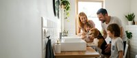 Happy Caucasian family with two children brushing teeth together in modern bathroom. Parents teaching kids proper dental hygiene habits in bright home interior.