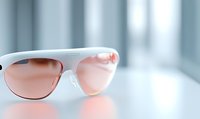 Modern white sunglasses with pink-tinted lenses on reflective surface against soft blurred background. Minimalist fashion accessory photography with selective focus.