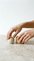 Hands gently touching wooden spheres on marble surface showcasing natural textures and mindful interaction in minimalist setting.