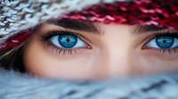 Young woman with striking blue eyes wearing winter knit hat and scarf in cold weather portrait for seasonal fashion and beauty concepts.