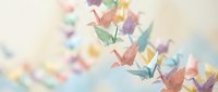 Colorful origami paper cranes floating in soft pastel sky creating dreamy artistic composition for meditation, mindfulness and creative projects.