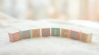 Pastel wooden alphabet blocks spelling SERVICES arranged in an arc on a soft white surface with a warm blurred background.
