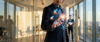 Professional businessman in dark suit interacting with futuristic holographic interface displaying glowing digital icons in modern glass office environment.