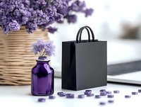 Purple dried flowers in woven basket and glass bottle with black shopping bag on white surface, elegant spa and retail composition with lavender accents.