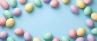 Pastel colored Easter eggs arranged as a frame border on a light blue background with copy space for text or design.