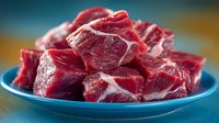 Fresh raw beef chunks cut into cubes on blue plate ready for cooking stew or braising, red meat protein ingredient for culinary preparation and recipes.