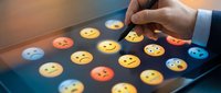 Businessman selecting yellow smiley face emoji on digital touchscreen display among colorful emotion icons representing customer satisfaction, feedback, and user experience rating.