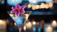 Pink lily floating on martini cocktail glass with blurred bokeh lights and candles creating romantic atmosphere for luxury restaurant or bar menu.