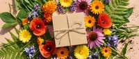 Colorful wildflower wreath with kraft paper gift box on rustic wooden background for seasonal celebrations and natural decorating projects.