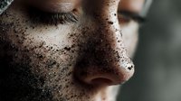 Close up macro shot of female face with coffee scrub particles on skin, showing natural beauty skincare routine and exfoliation treatment for spa and wellness concept.