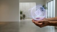 Hands holding glowing holographic sphere with atomic structure in modern office space representing innovation, technology and scientific research concepts.