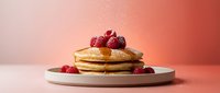 Stack of golden pancakes topped with fresh berries and syrup on white plate against warm pink background for breakfast menu design.