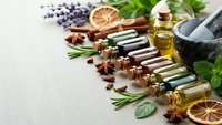Natural essential oil bottles with herbs, spices and aromatherapy ingredients on wooden background for wellness, spa treatments and holistic healing practices.
