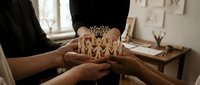 Young woman wearing ornate golden crown held by hands in studio setting, suitable for royalty, beauty, fashion, and editorial projects.
