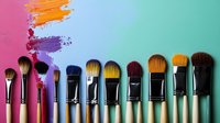 Professional makeup brushes arranged in a row with colorful paint strokes on gradient background, showcasing artistic tools for beauty and creative work.