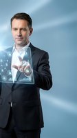 Professional businessman in dark suit interacting with futuristic holographic security interface displaying data analytics and cybersecurity elements.