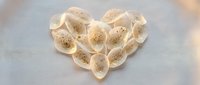 Heart-shaped arrangement of sliced bananas with chia seeds on marble surface for healthy breakfast and romantic food styling concepts.