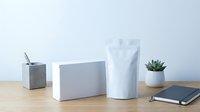 Minimalist white product packaging mockup with boxes and pouch on wooden desk for branding design presentation and marketing materials.