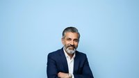 Mature male professional with salt-and-pepper beard wearing navy blazer and white shirt against blue background. Corporate headshot for business, leadership, and executive portraits.