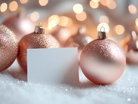 Rose gold Christmas ornaments and blank white card on snow with festive bokeh lights background, elegant holiday mockup for seasonal greetings.