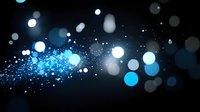 Glowing blue and white bokeh lights with sparkling particles on dark background create magical atmospheric effect for festive designs and celebrations.