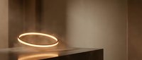 Glowing neon ring light on wooden surface in modern interior space, suitable for contemporary design projects and minimalist decor concepts.