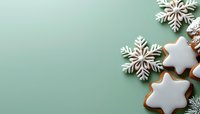 Festive snowflake cookies with white icing on mint green background. Winter holiday baking composition with gingerbread stars and decorative elements.