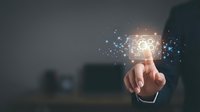 Businessman touching glowing light bulb with digital particles dispersing, representing innovation, creative ideas, and smart business solutions for technology concepts.