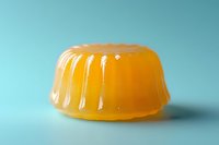 Orange jelly dessert with ribbed surface on turquoise background, soft focus food photography showing translucent gelatin texture and glossy shine.