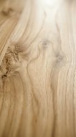 Light oak wood surface with natural grain patterns and knots, shot at shallow depth of field for flooring, furniture, and interior design projects.