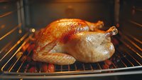Whole roasted golden brown turkey with crispy skin cooking in oven with vegetables. Traditional holiday dinner preparation showing juicy poultry on rack.