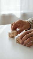 Hands arranging wooden blocks with healthcare symbols including cross and medical icons on white table for wellness planning concepts.