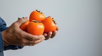 Man holding fresh ripe oranges in hands against white background. Farmer or gardener displaying citrus fruit harvest for agriculture, farming, or healthy eating concepts.