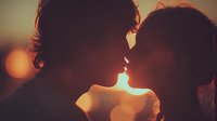 Romantic couple silhouettes touching foreheads at golden hour sunset with warm bokeh lights creating intimate atmosphere for love and relationship concepts.