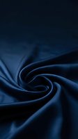 Luxurious dark navy blue silk fabric with elegant swirling folds, smooth satin texture, and deep shadows for fashion or luxury branding.