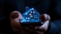 Glowing blue hologram of smart house floating above mobile phone in hands, digital home automation concept with sparkle particle effect.