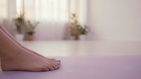 Close-up of bare feet on purple yoga mat in bright studio with blurred plants in background, perfect for wellness and fitness content.