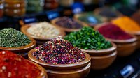 Vibrant colorful spices and seasonings in wooden bowls at market stall, selective focus on multicolored peppercorns, fresh herbs and aromatic ingredients for cooking.