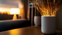 Minimalist white ceramic vase with dried wheat stalks on wooden table at sunset, creating warm atmospheric mood with golden light and soft bokeh background.