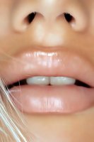 Close-up macro shot of natural pink lips and white teeth showing partial face features. Soft focus portrait highlighting facial details and skin texture.