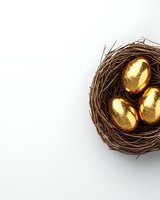 Golden eggs nestled in brown twigs nest on white background, symbolizing wealth, investment and financial security concept for business presentations.