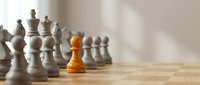 Orange chess pawn standing out among white pieces on wooden board, symbolizing leadership, uniqueness and strategic thinking in business concepts.